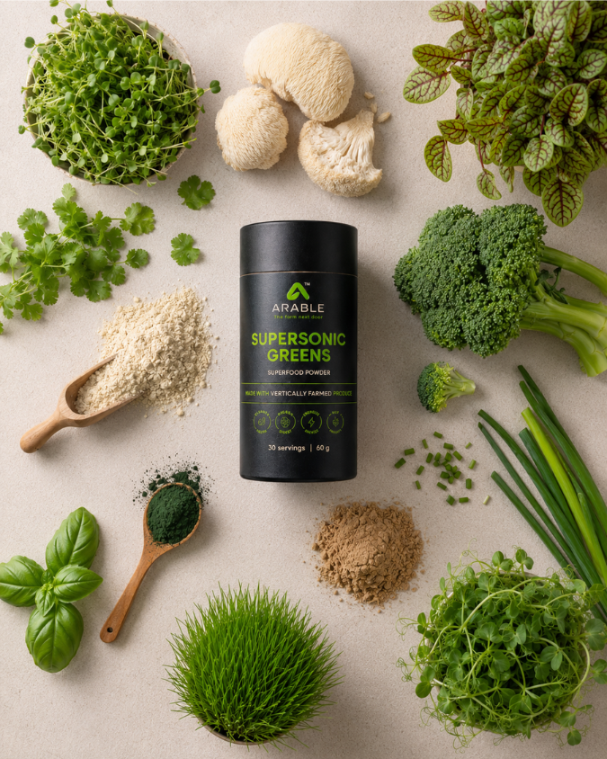 Supersonic Greens powder surrounded by microgreens, lion's mane mushroom, spirulina and plant-based ingredients